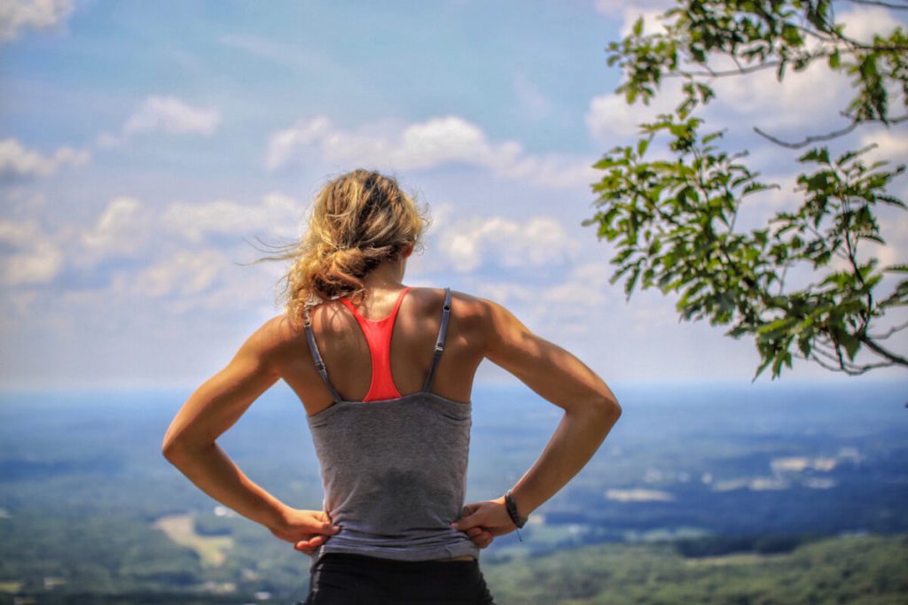 fitness woman standing near tree looking below