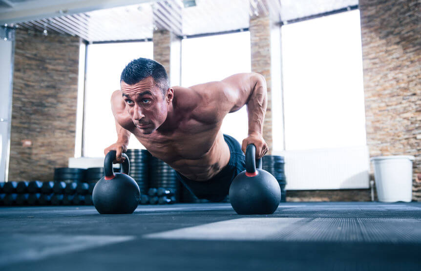 man doing push ups on kettle ball in CrossFit gym