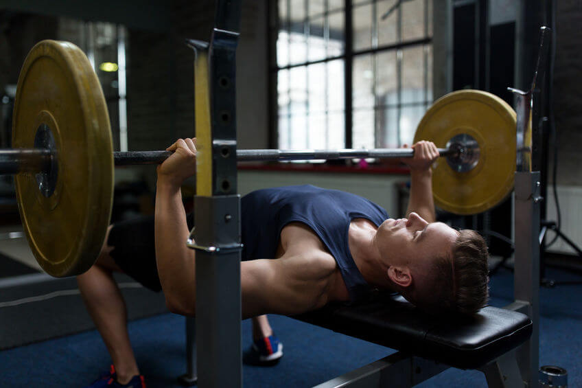 man work out using barbell and weight bench in garage gym