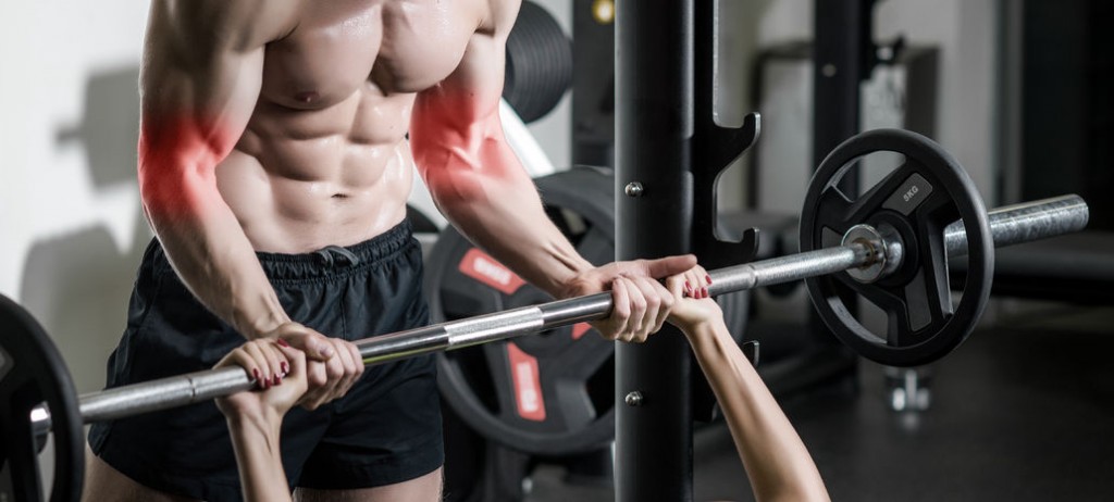 personal trainer with barbell flexing muscles in gym