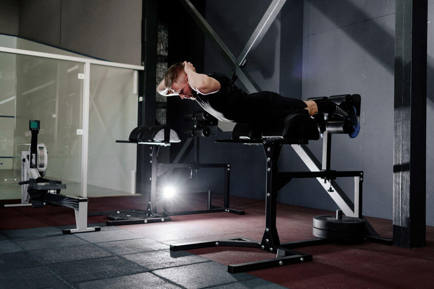 young man training on glute ham developer at the gym