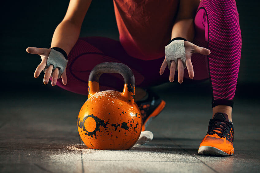 woman wearing CrossFit hand grips and using kettlebell