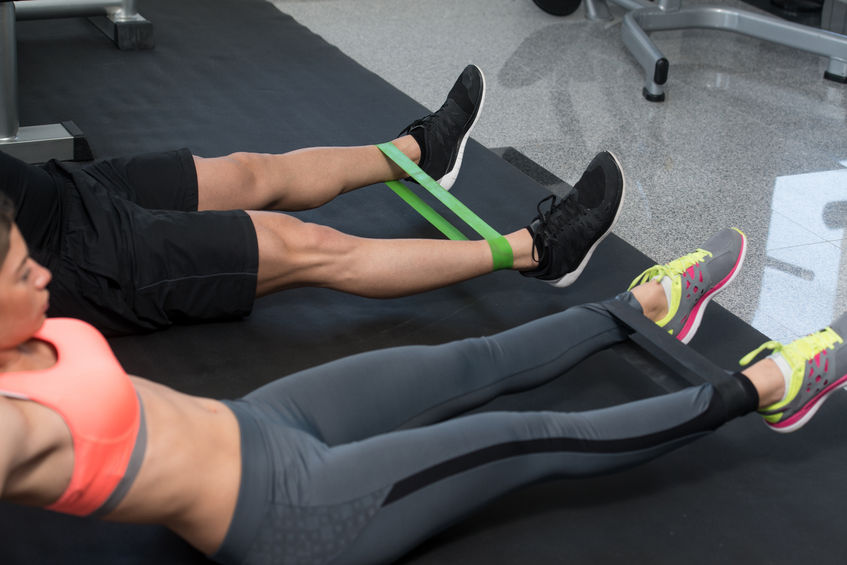 young couple train together-with-resistance bands a leg exercise