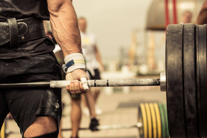 bodybuilder lifting heavy barbell wearing wrist wraps