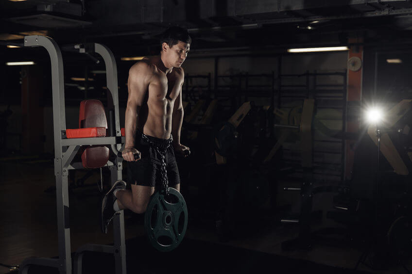 man working out in gym doing exercises on power tower