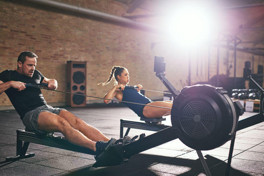 Two young sportsmen training on rowing machines