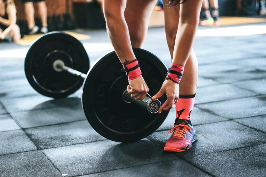 person wearing wrist wraps and holding barbell in CrossFit gym