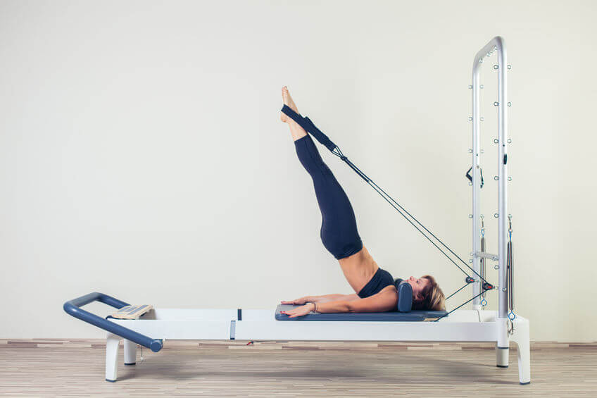 Pilates reformer workout exercises woman at gym indoor