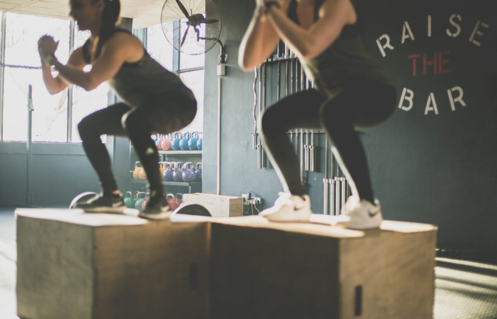 two women wearing compression leggings and jumping on plyo box