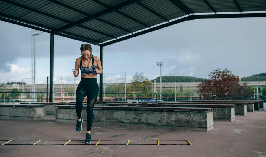 woman training jumping on an agility ladder