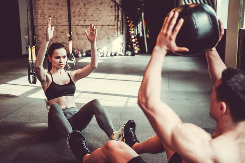 couple is working out with medicine ball in gym