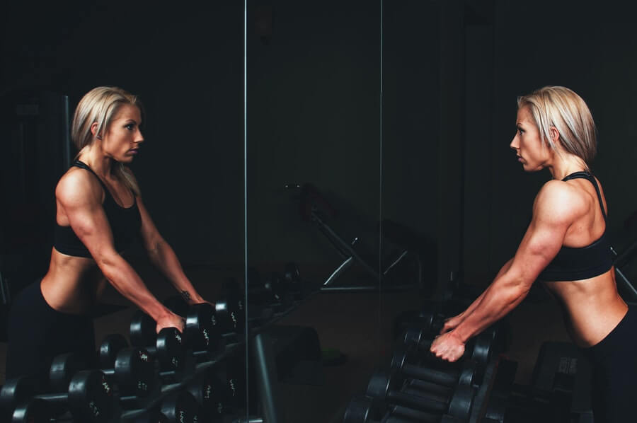 woman in the gym close to dumbbells rack