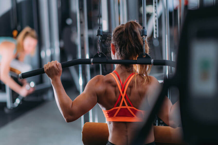 woman doing exercise on a lat machine in gym