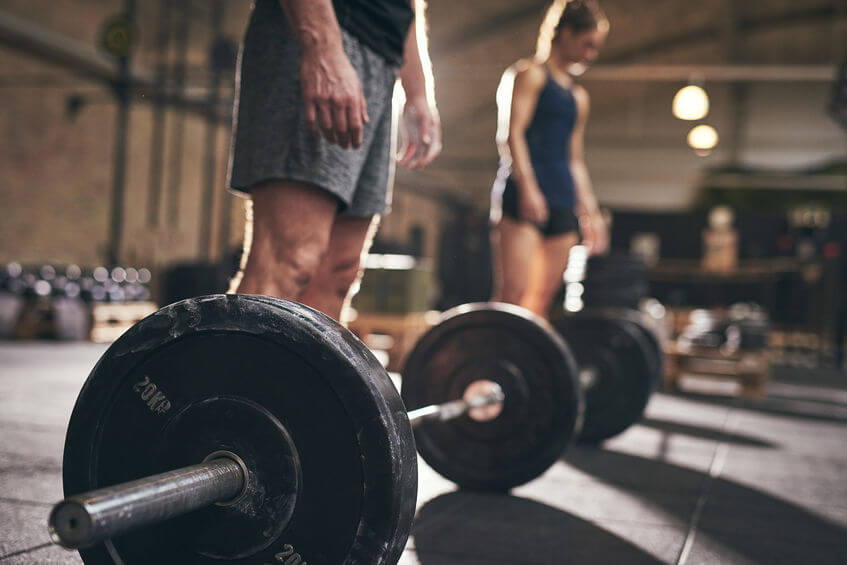 Fit people standing at barbells before exercise