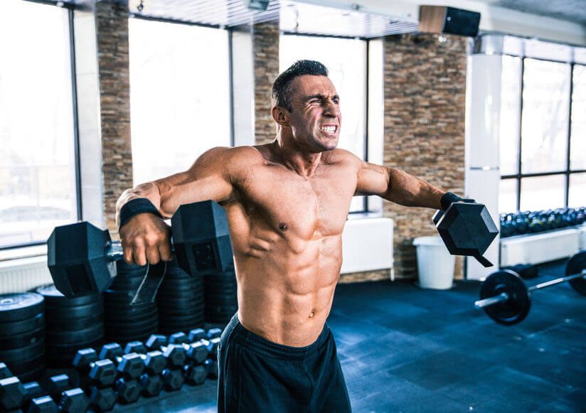 Muscular man lifting rubber hex dumbbells at gym