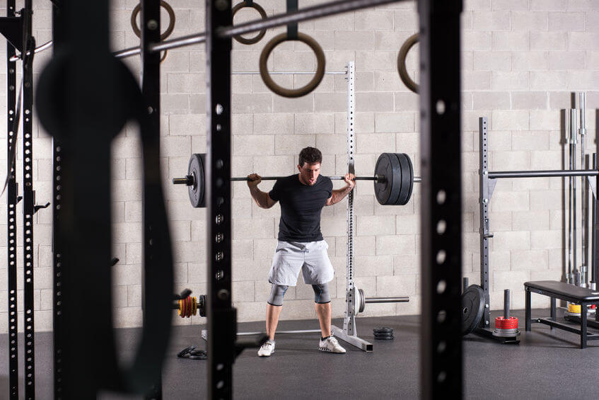 man lifting heavy barbell on squat rack