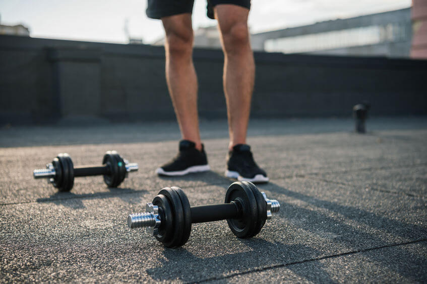 sportsman standing near adjustable dumbbells