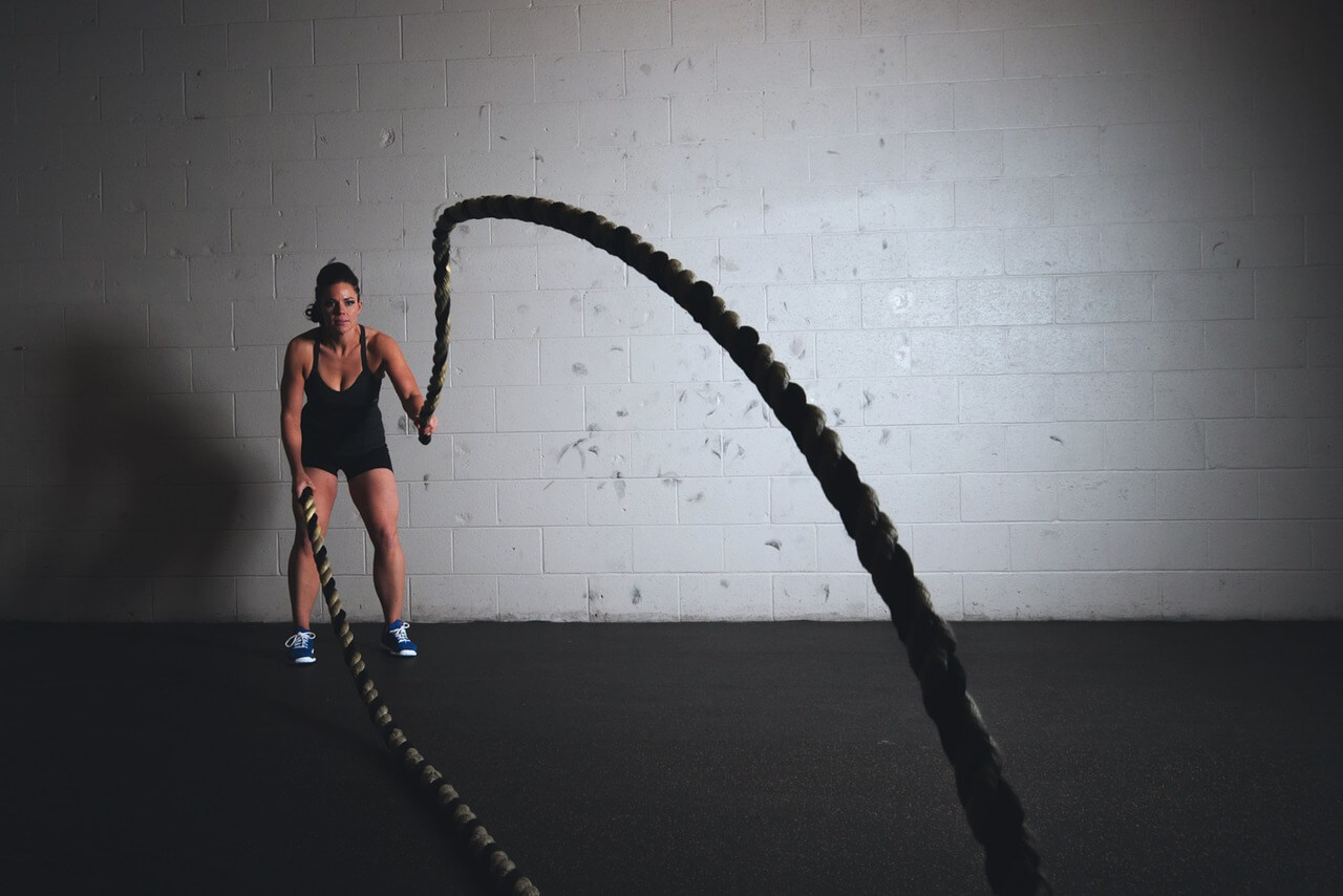 women doing battle rope workout in gym