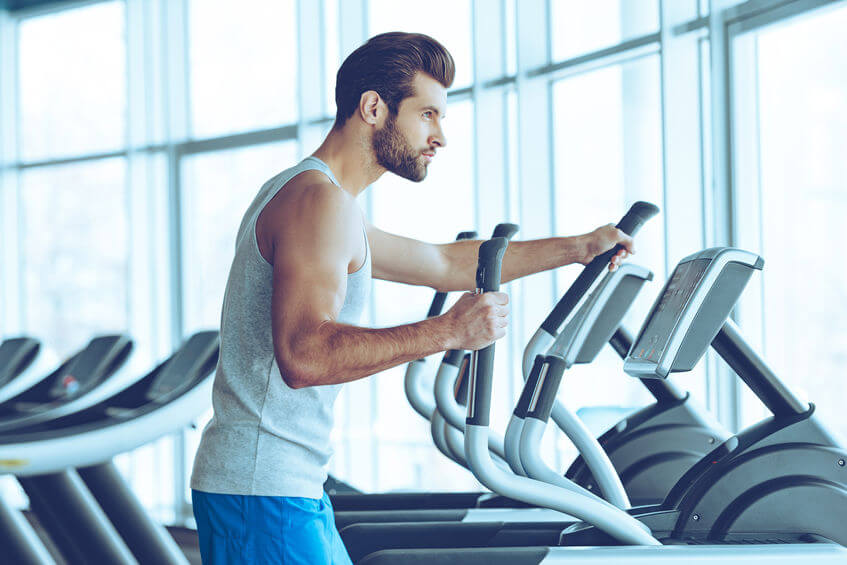 young man working out on stepper machine at gym