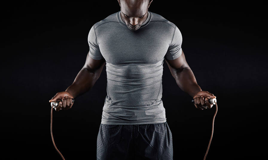 Man with compression shirt exercising with jumping rope