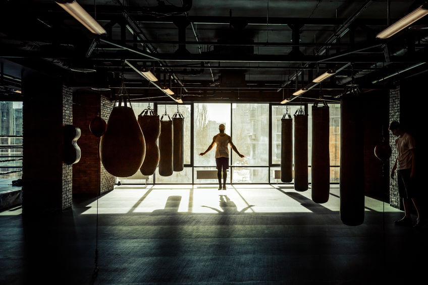 Men warming up in boxing gym with punching bags