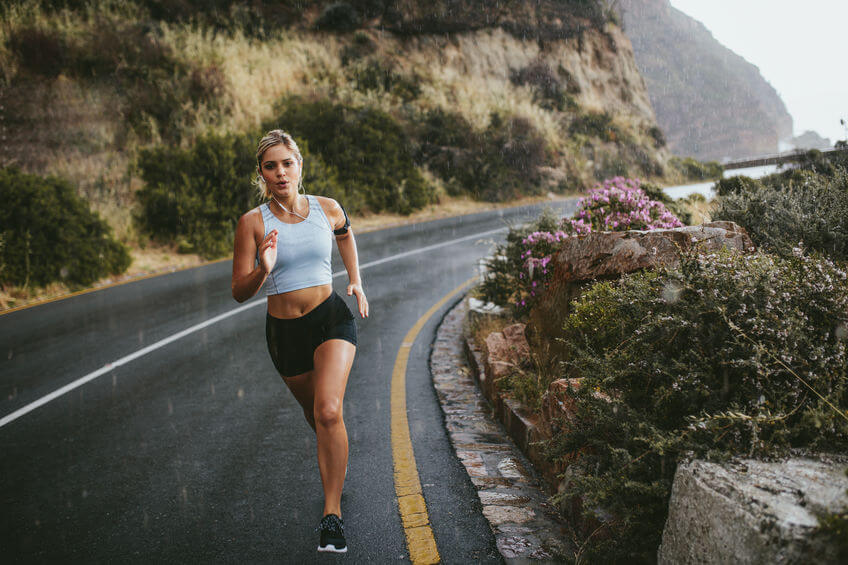 female athlete running on road during rain