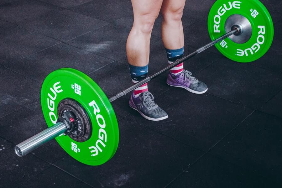 person standing in front of green Olympic barbel at the gym