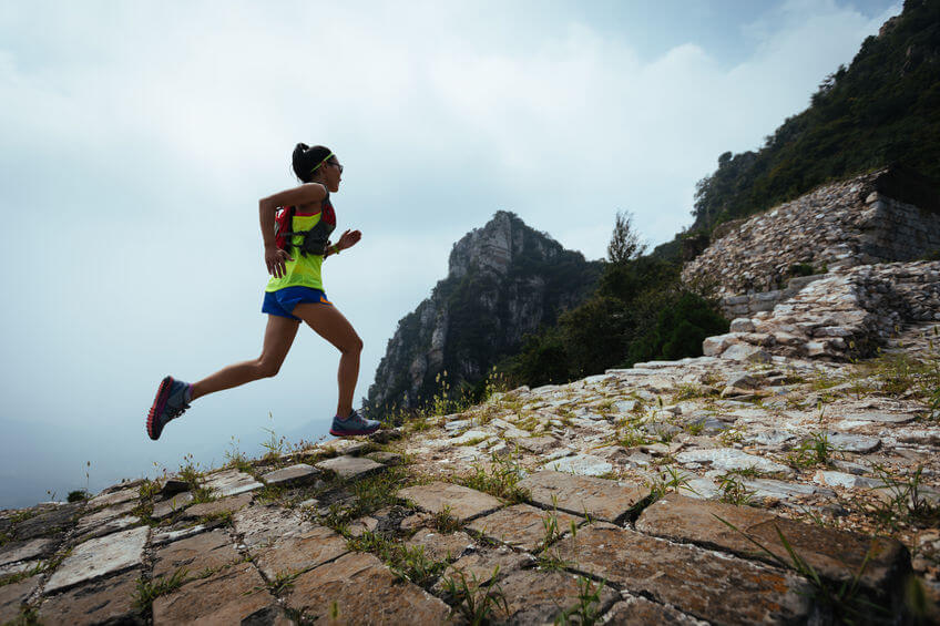 woman trail runner running with hydration backpack