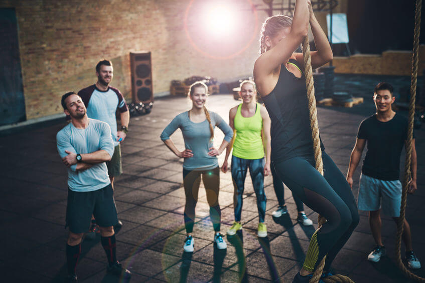 women climbing a rope in a CrossFit gym