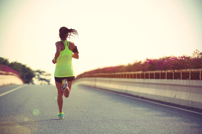 young woman runner running on city road