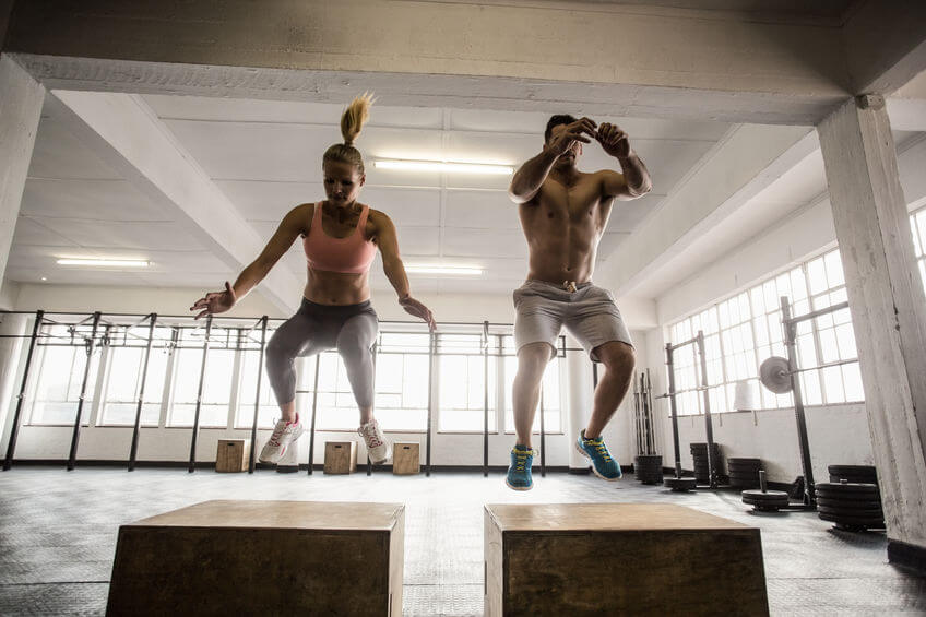 couple doing set of box jumps in crossfit gym