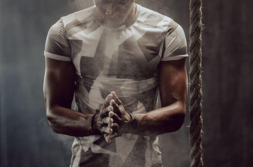 man chalking his hands before climbing a rope - grip training