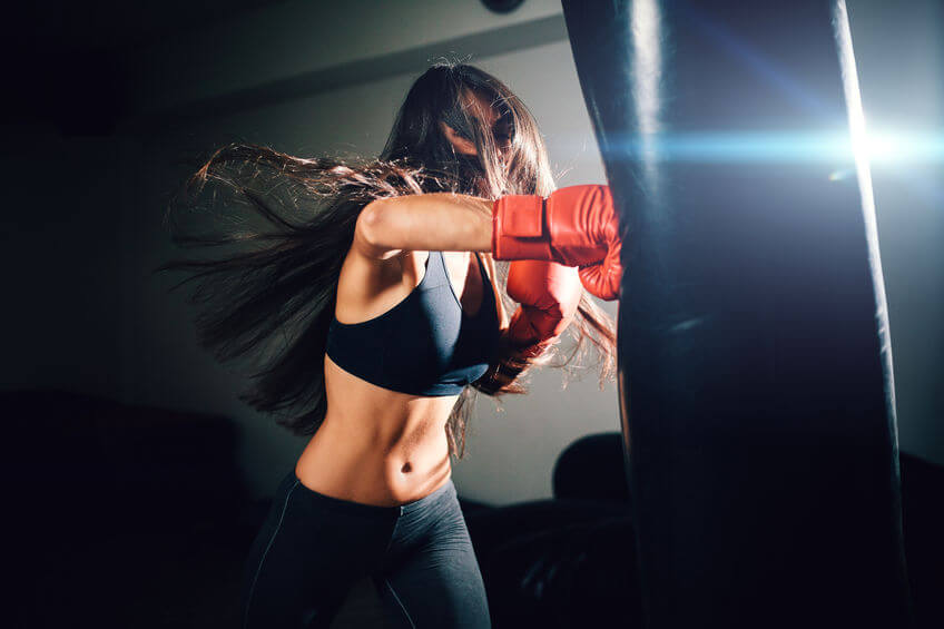 woman punching heavy bag with boxing gloves