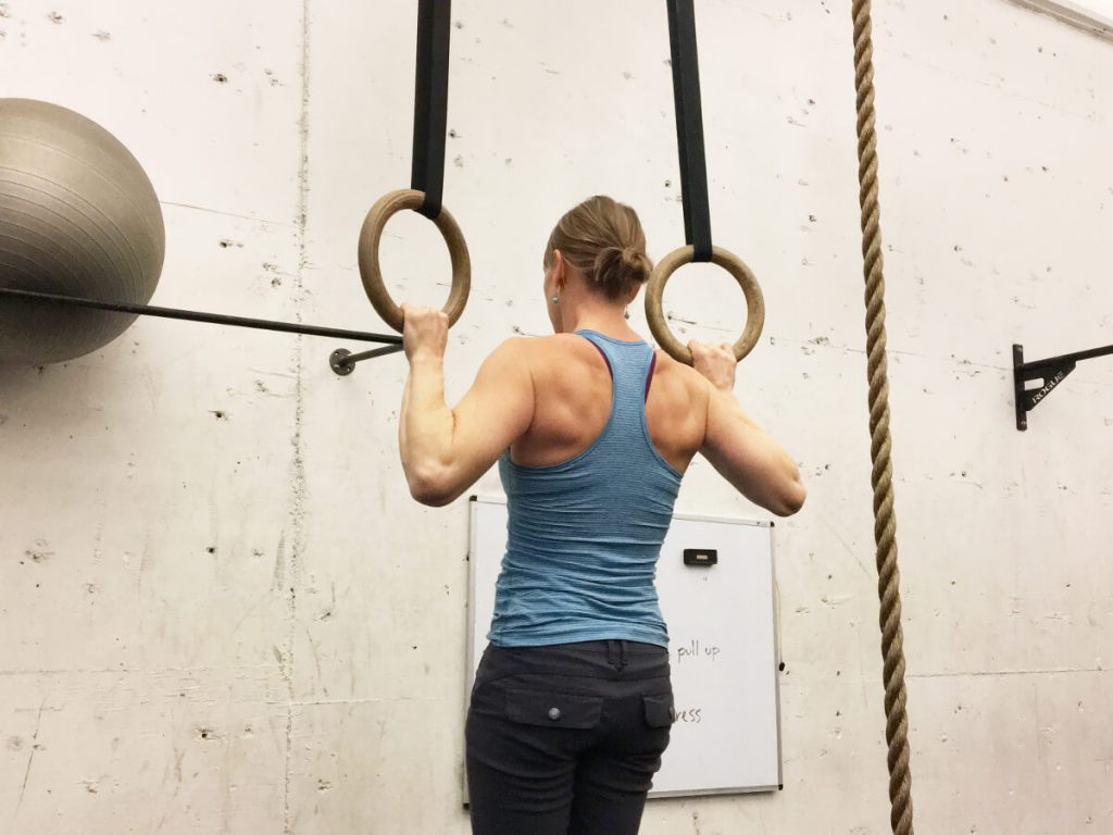 woman using gymnastic ring in crossfit gym