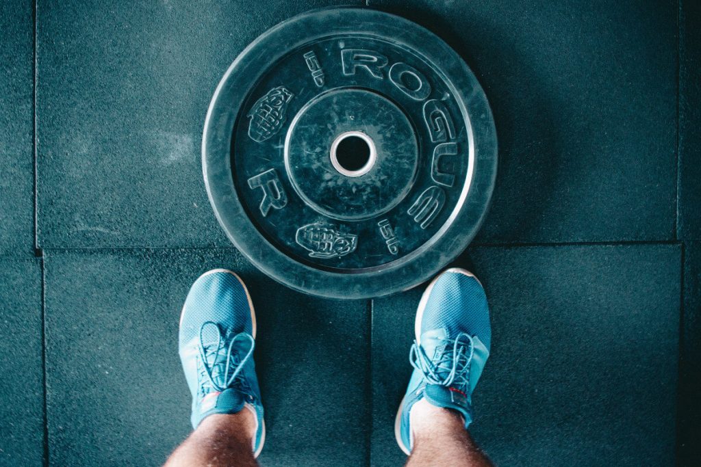 person standing beside Rogue barbell plate