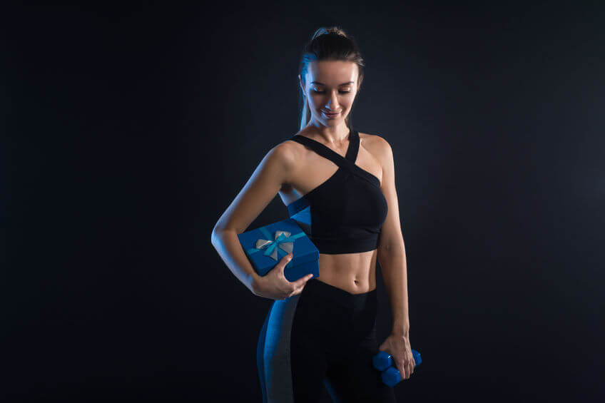 fitness woman holding dumbbells and gift box in her hands