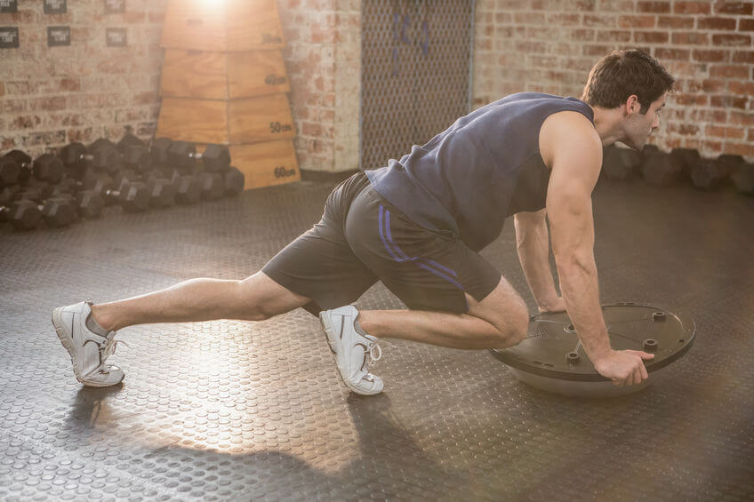 man doing exercise with Bosu ball at the gym