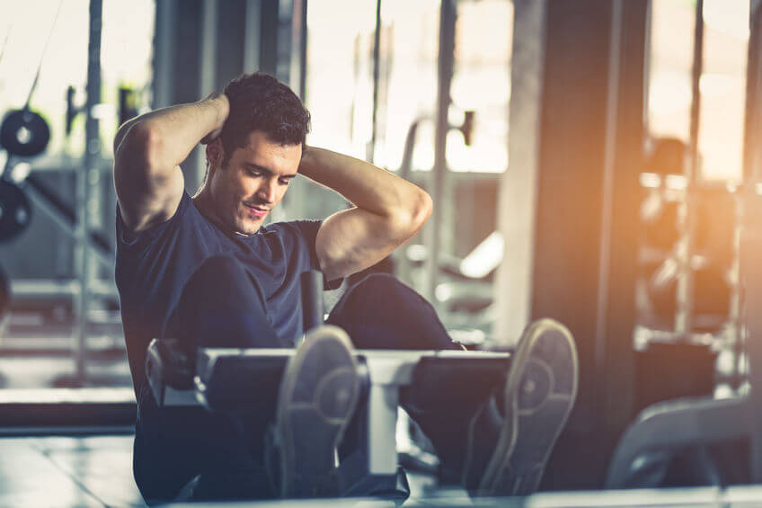 man doing sit ups on ab bench at the gym