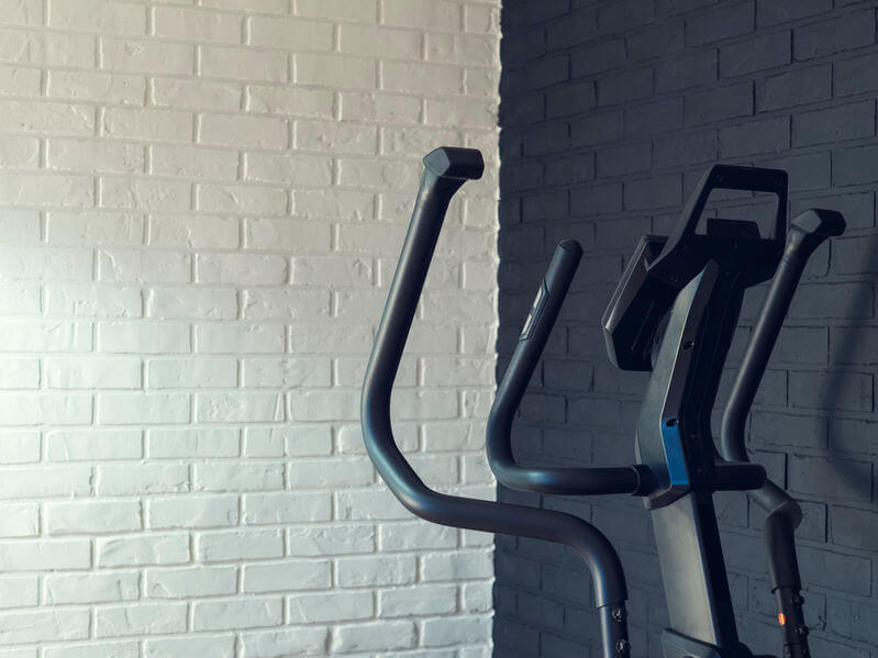 elliptical trainer against a brick wall at home gym