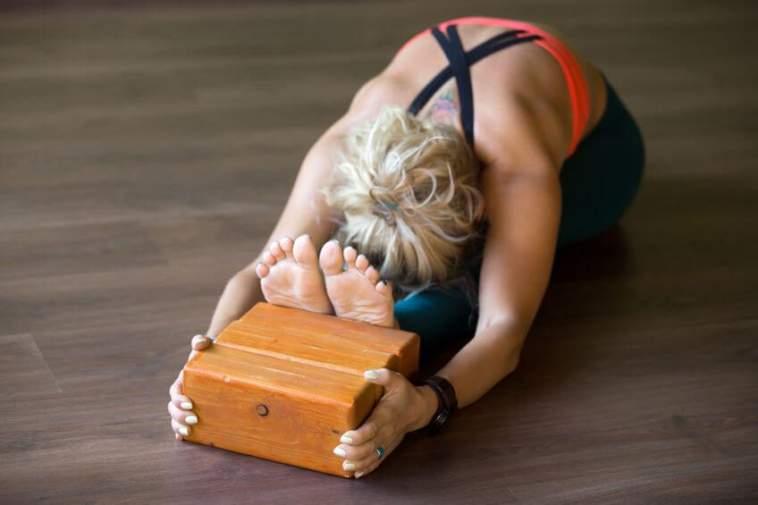 woman doing yoga exercise and using wooden yoga blocks