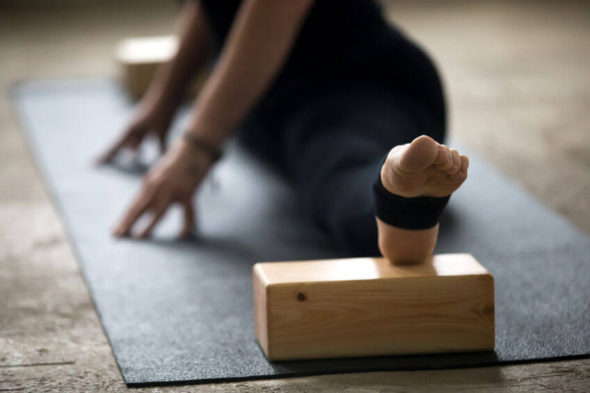 woman practicing yoga pose using blocks for deep stretch