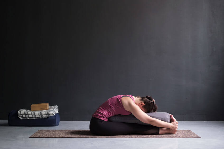 woman practicing yoga with yoga bolster