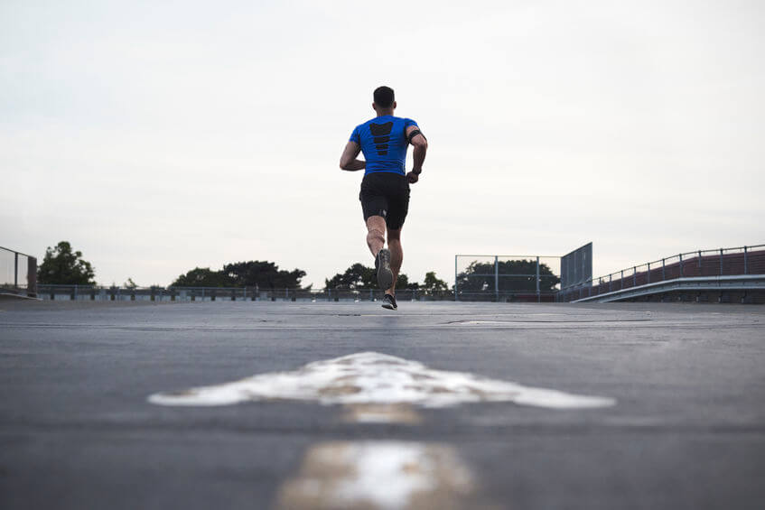 male athlete running on a road wearing compression gear