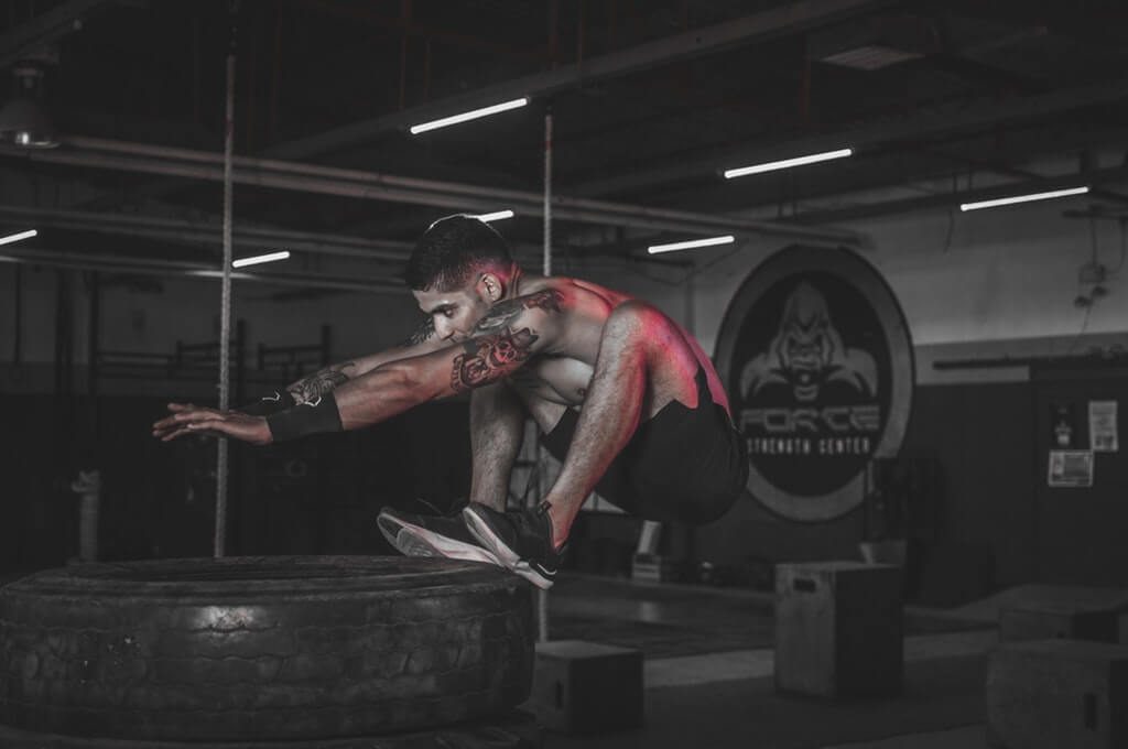 man jumping on tires at the CrossFit gym