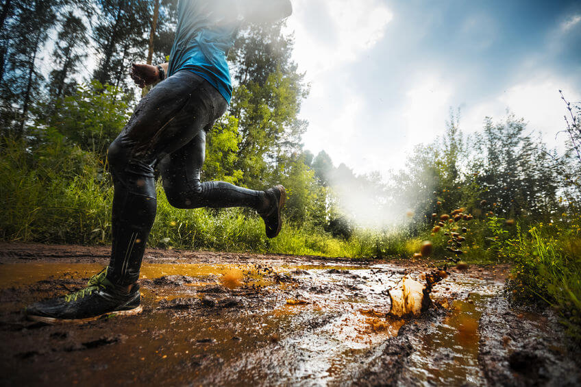 trail runner moving through the dirty puddle