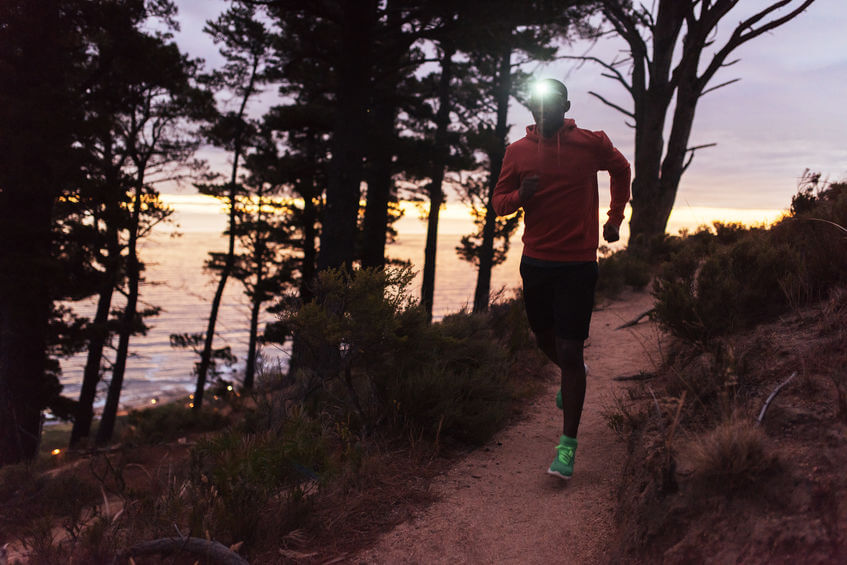 trail runner wearing a headlamp running at dusk