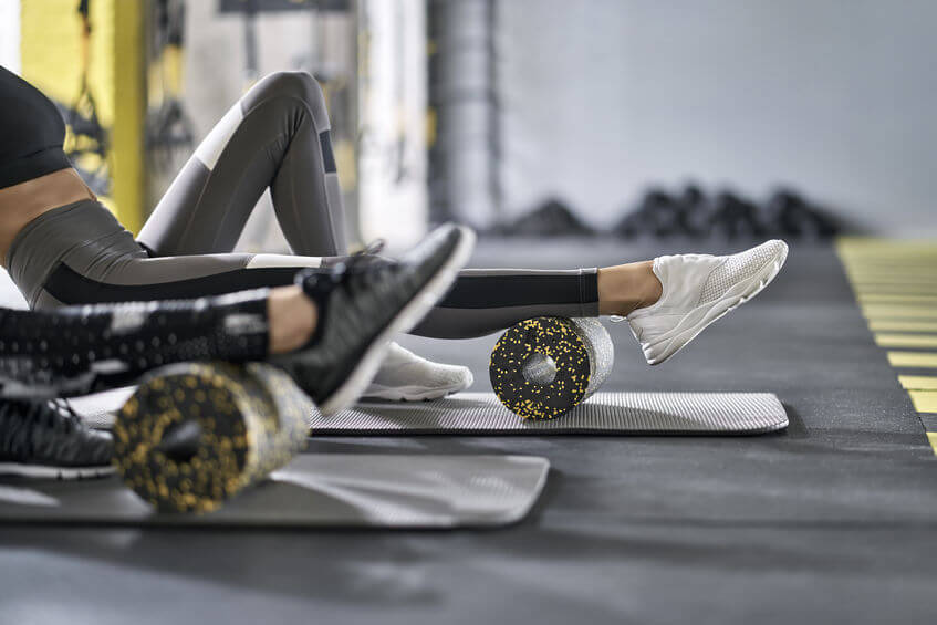 two girls training in gym using foam rollers