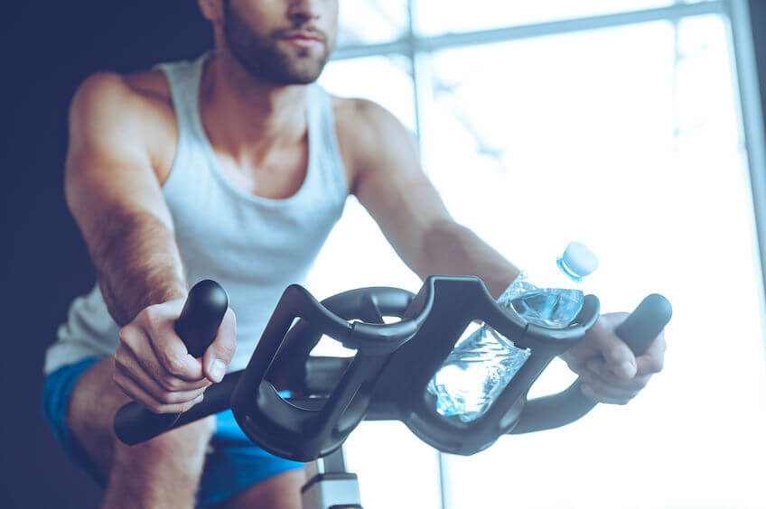 man cycling at gym using exercise bike