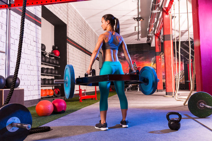 woman at gym doing squat exercise with hex trap bar