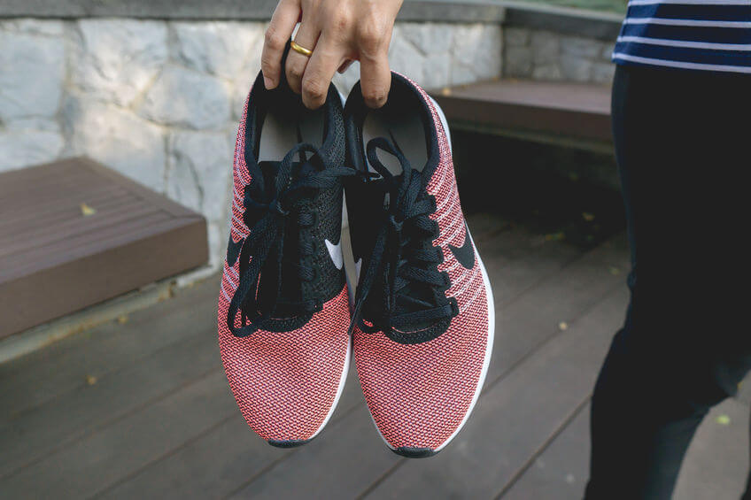 woman holding pair of pink nike running shoes